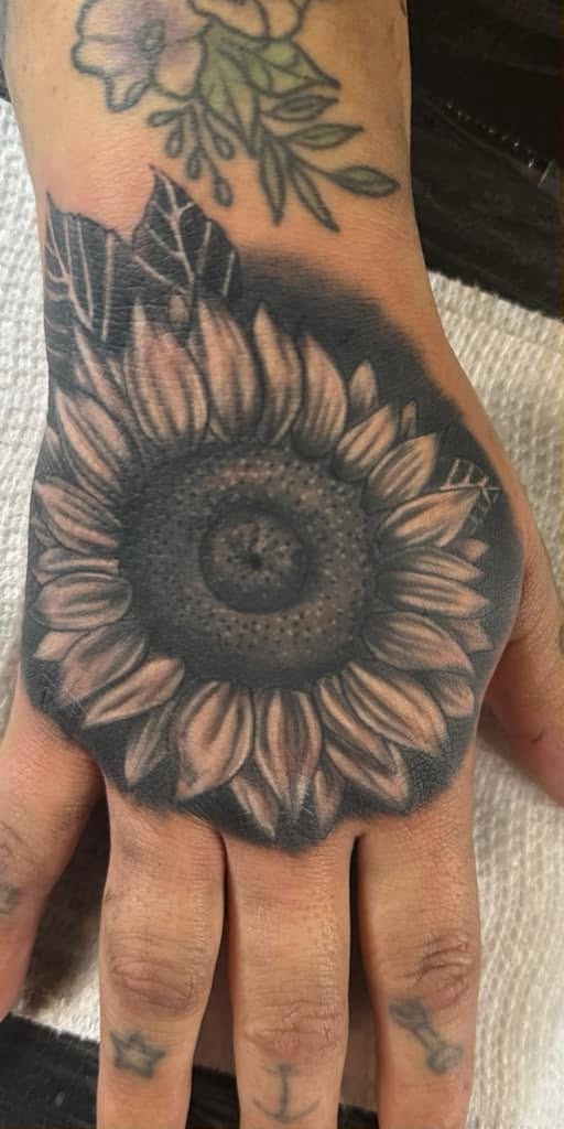 Black and gray sunflower across the back of a hand